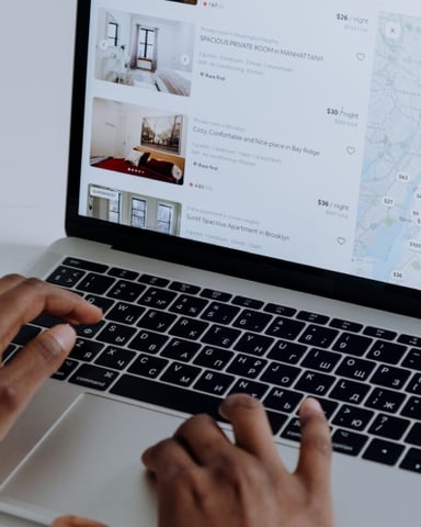 Hands browsing Airbnb listings on a laptop